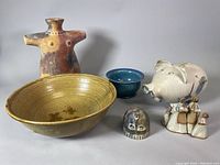 Full view of all pottery items: large bowl, shirt planter, angel figurine, blue bowl, pig planter, small round pottery piece, and group of figurines.