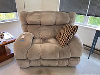 Front view of oversized beige power recliner with throw pillow on the right arm.