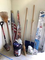 Full view of all items including a folded American flag, garden tools, roof rake in box, and ice melt container.