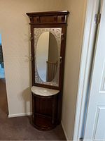 Front view of tall dark wood hall tree with oval mirror and metal hooks