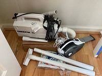 Full view of Oreck XL vacuum, Black & Decker handheld vacuum, two extension wands, and other vacuum accessories on the floor.