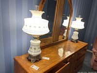 Two matching glass lamps placed on a wooden dresser with mirror background, showing overall appearance.