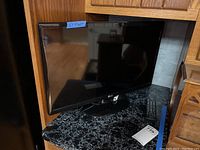 LG 24LB451B 23-inch television on countertop with remote control beside it, showing overall condition and size reference.
