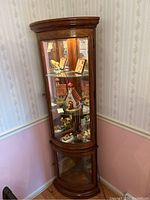 Curved glass corner cabinet positioned against two walls showing contents and overall structure
