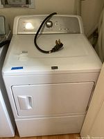 Front view of white Maytag electric dryer showing control panel, door, and 3 or 4 wire power plug on top.