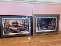 Full view of two framed Terry Redlin winter prints, side by side, leaning against a pink wall