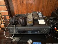 Sony VHS VCR with 3 remotes and headset on top showing full front view and controls