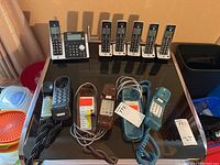 Full lot layout showing two vintage AT&T phones, Sony corded phone, and cordless phone set with answering machine, charging docks, and handsets on black table.