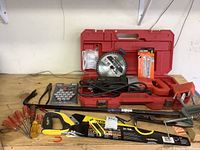 Full view of tools on workbench showing Milwaukee reciprocating saw in case, various hand tools including screwdrivers and clamps