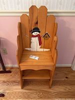 Front view of wooden bench with painted snowman on backrest.