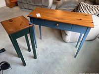 Two wood tables with painted legs and natural wood tone tops seen from an angle, showing overall condition and design.