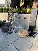 Full view showing bird cages, wicker ottoman, lamp shade, metal hanging spheres, ceramic planter, and artificial succulent planter.