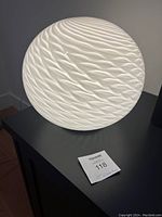 White globe table lamp with textured wave and swirl pattern, illuminated in some angles, showing detailed surface design and size reference with a 13 inch measurement note.