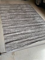 Full view of the rectangular grey and cream area rug on the floor showing its size and pattern.