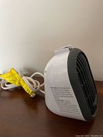 Side view of Honeywell portable heater showing caution label and white power cord with yellow tag