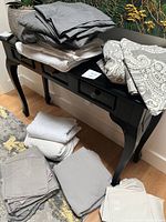 Assorted king size bedsheets and pillowcases in solid gray, white and beige colors and patterned gray and white duvet cover.