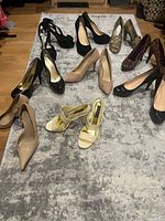 Overview image showing nine pairs of ladies high heels in different colors and styles arranged on a rug.