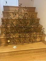 Two metal leaf wall art pieces displayed on wooden stairs showing full size and detail