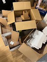 Overview of opened boxes containing kraft envelopes, cardboard boxes, and crinkle paper packing fill.