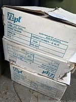 Boxed NPT brand white mosaic tile sheets, showing label details including 'Mini Koyns' pattern, 20 sheets per box, made in Indonesia.