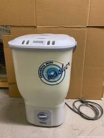 Front view of the white mini washing machine with logo and power cord.