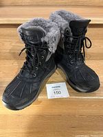 Front view of UGG Adirondack black winter boots with lace-up front and gray faux fur lining.