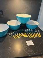 Full view of flatware and 4 ceramic bowls on dark countertop