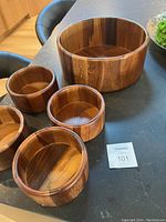 Photo showing the set of one large and four smaller wooden salad bowls on a table.