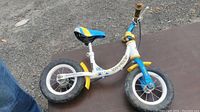 Side view of the WeeRide balance bike on a dark surface showing the frame, wheels, and seat