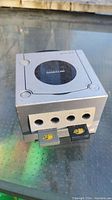 Silver Nintendo GameCube console front with two memory cards inserted in front ports, showing logo and details on cards.