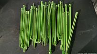 Photo showing green plastic garden pegs laid out horizontally from a top-down view, displaying quantity and condition