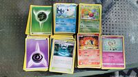 Stacks of Pokémon trading cards showing energy cards, character cards such as Sealeo, Weepinbell, Cyndaquil, Cutiefly, and trainer cards.