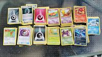 Multiple stacks of assorted Pokemon cards laid out on a surface showing various types including Psychic, Fire, Water, Grass, and Electric energy cards plus character and trainer cards.