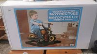Front of box showing product image of child on wooden rocking motorcycle and product name