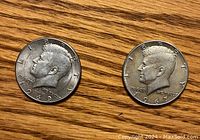 Obverse side of two Kennedy half dollar coins dated 1969 and 1967 showing John F. Kennedy profile and inscriptions.