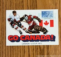 Front of vintage hockey postcard showing illustration of Canadian and Soviet players, text 'GO CANADA!' and postage stamps.
