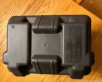 Top view of the closed black marine battery box showing the molded features and labeling.