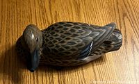 Top view of hand-carved and painted wooden duck decoy showing detailed feather pattern and black beak.