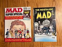 Photo showing MAD Super Special Number 18 and The Nostalgic MAD Number 4 laid side by side on wood floor.