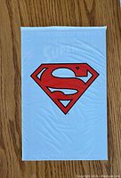 Front view of the sealed comic book in a white bag featuring a large red Superman 'S' shield.