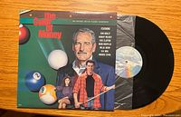 Front of The Color of Money vinyl record cover with artwork depicting billiard balls and main actors.