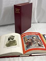 Maroon binder labeled 'American History Illustrated' with one binder open showing magazine pages featuring historical bust and illustrations.