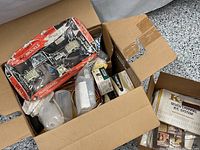 Box containing various model plane parts packed together including translucent fuel tanks and boxed components.