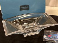 Nambe Planar clear crystal glass flare bowl placed next to its original box showing bowl shape and clarity