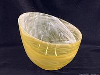 Oval yellow art glass bowl with swirling opaque yellow and white marbled paint, shown from angled front-left view