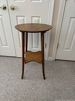 Front view of the oak round accent table showing the legs and shelf below the top.