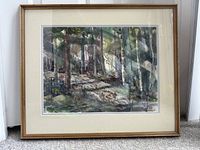 Frontal image of the framed watercolor artwork titled "Woodland Shades" depicting a wooded forest scene. The frame is golden wood with a cream and gray mat. The painting is behind glass and resting on carpet.