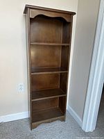 Front view of vintage solid hardwood 4-shelf bookcase showing fixed shelves and scalloped edge details