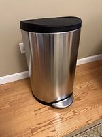 Side view of the stainless steel step trash canister with black plastic step pedal and lid.