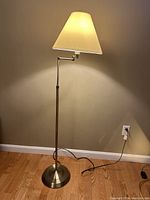 Floor lamp lit and unlit showing full height and base with an articulating arm and cream fabric shade.